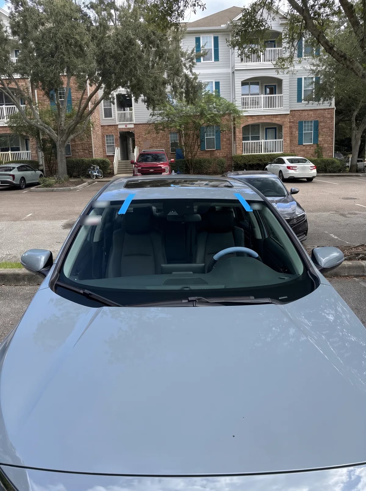 A grey sedan in an apartment parking lot with the windshield Bang AutoGlass replaced in Tampa, FL